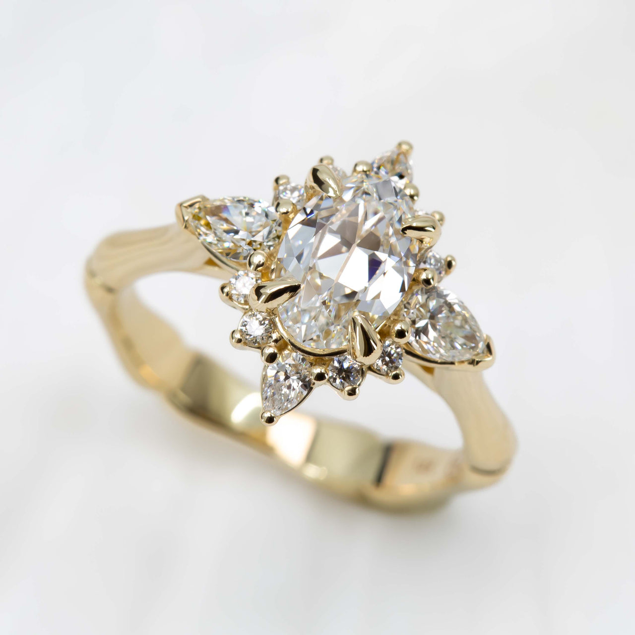 Gold ring with a central diamond and pear-shaped side stones on a white background