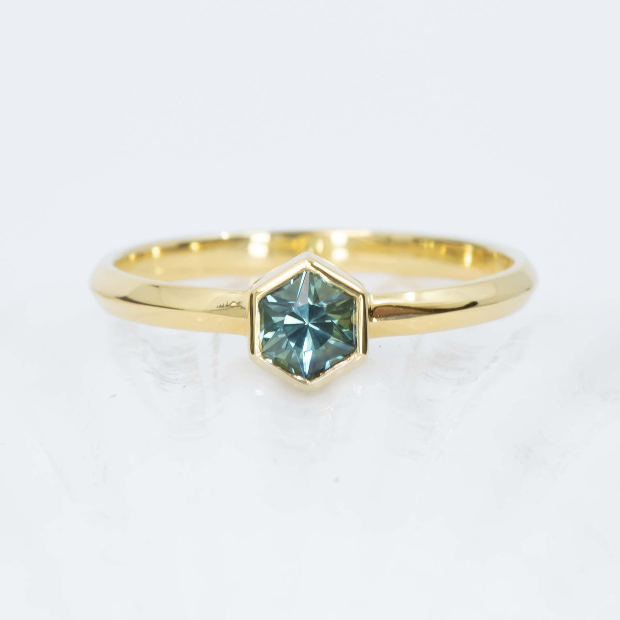 Gold ring with a blue sapphire on a white background